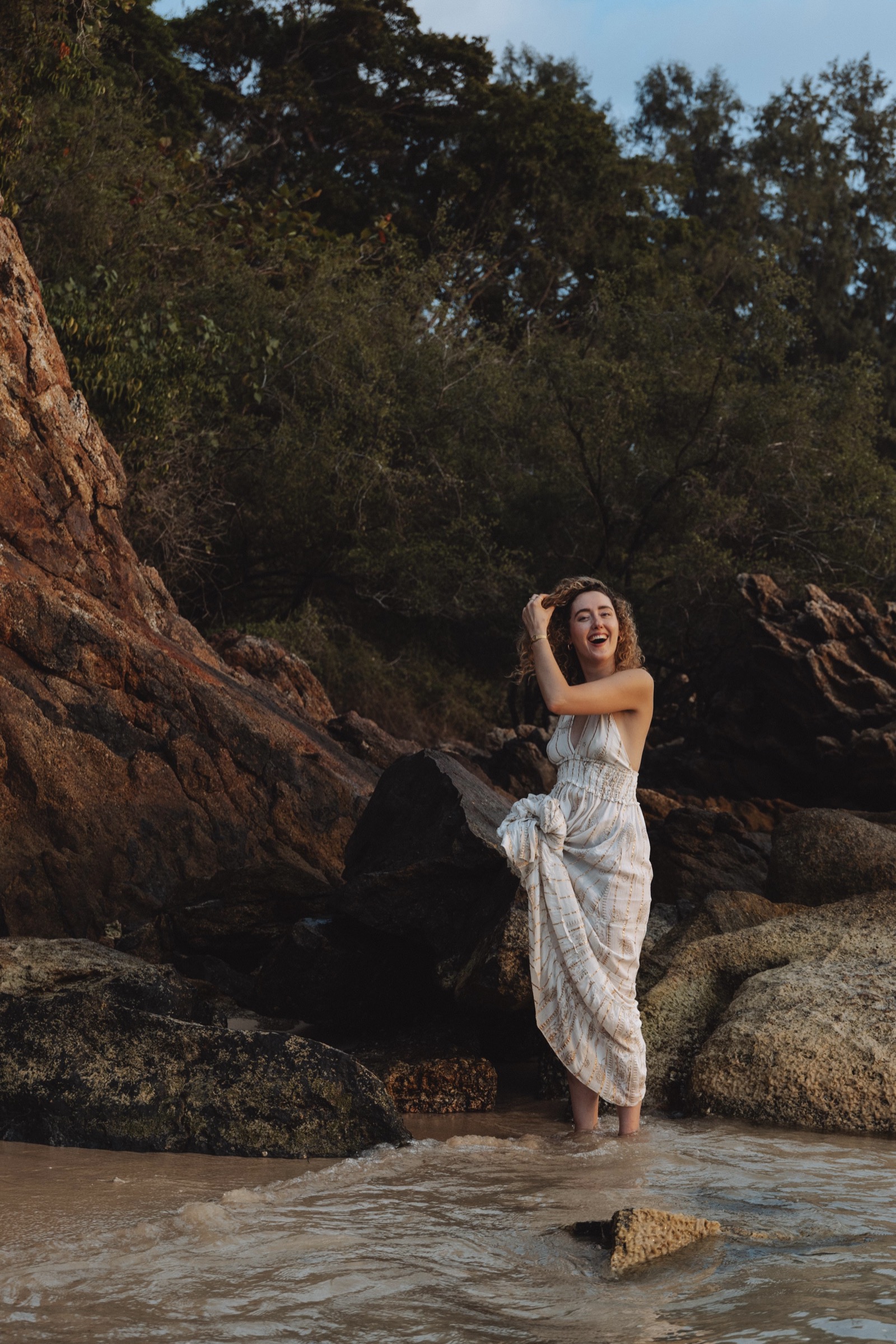 Camilla lachend zwischen Felsen am Strand